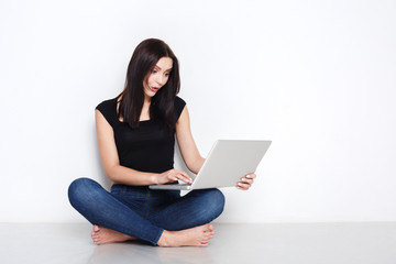 Fototapeta premium Woman using laptop sitting on the studio floor