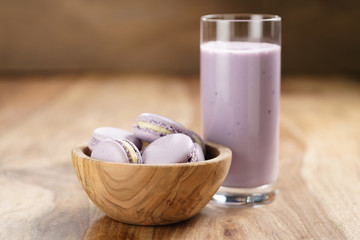 violet macarons in wood bowl with blueberry yogurt on wooden table