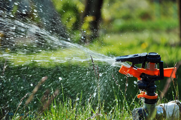 The process of watering a lawn with a sprinkler.