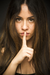 Naklejka premium Portrait of a beautiful woman Commanding silence on black background