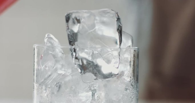 Rose lemonade pouring on ice cubes on first plane