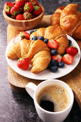 Delicious breakfast with fresh croissants and ripe berries on old marble background