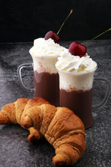 Iced coffee with whipped cream in tall glass and fresh croissant