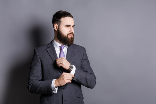 Bearded man in suit adjusting sleeves copy space