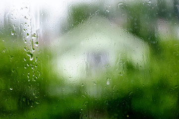 Wet window with drops, raining in a countryside