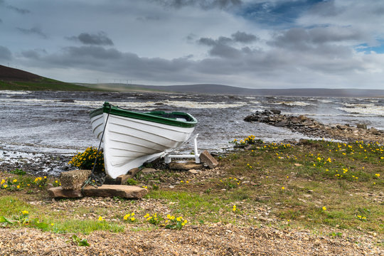 Rowing boat on shore of a stormy Scottish Loch, Orkney UK