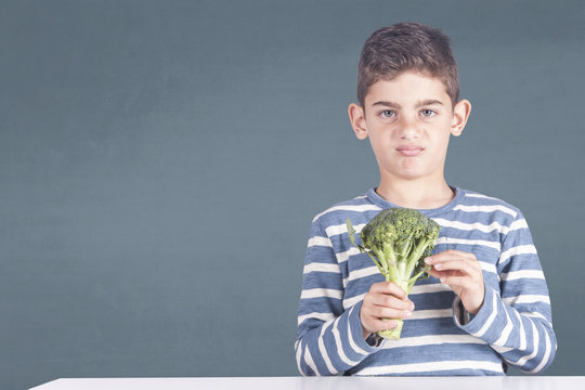 Little boy grimacing refusing to eat his broccoli