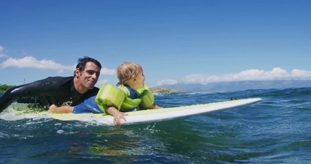 Father teaching son to surf tandem surfing
