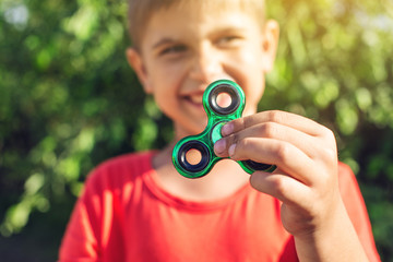 A boy plays with spinner twisting it in his hand on outdoors. Trends in children's anti-stress toys