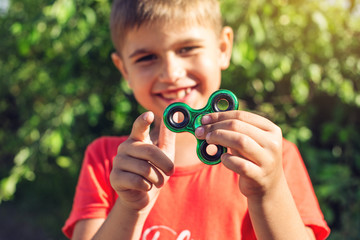 A boy plays with spinner twisting it in his hand on outdoors. Trends in children's anti-stress toys