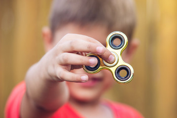 A boy plays with spinner twisting it in his hand on outdoors. Trends in children's anti-stress toys