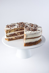 Isolated beautiful homemade layered sponge cake with white cream in rustic style with the cut out piece