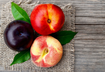 Fresh ripe organic peach,plum and chinese flat peach on old wooden table.Diet,healthy food,raw food concept.Selective focus.