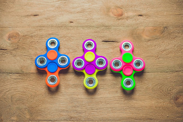 Colored fidget spinners stress relieving toy on wooden background
