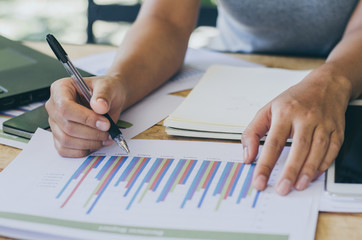Businesswomen analyzing investment charts on the desk. Pen in hand