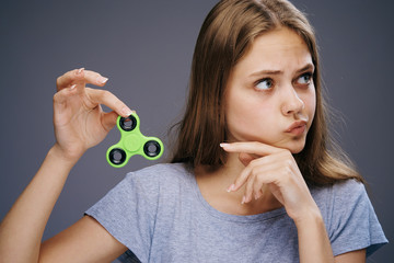 Beautiful young woman on a gray background holds a spinner