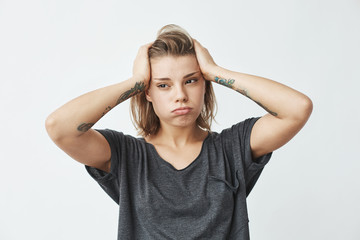 Young beautiful nervous upset girl thinking holding head over white background.