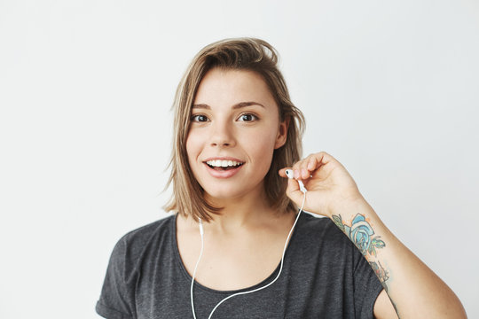 Nice young girl in headphones smiling looking at camera over white background.