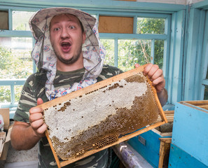 Beekeeper holding in hands Bee honeycombs of wax in a wooden frame.