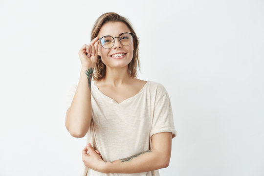 Young Pretty Girl Smiling Looking At Camera Correcting Glasses Over White Background.