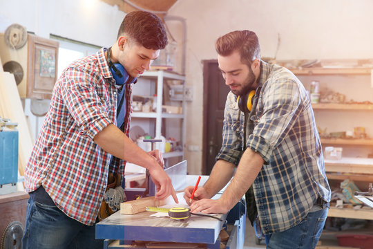 Carpenters applying marking onto drawing in workshop