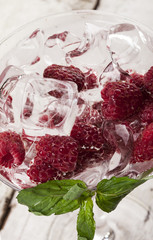 Closeup of summer cold drink with raspberry, mint and ice in glass on white background