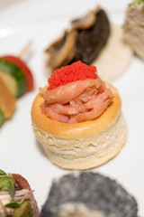 Different types of canapes, placed on white plates, finger food, light brown background