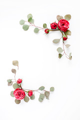 Border frame with red rose flower buds and eucalyptus branches isolated on white background. Flat lay, top view. Floral background