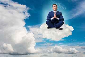 Businessman meditating in the sky