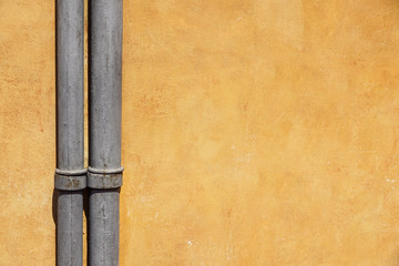 Weathered wall with pipe (gutter). Detail of the facade of a house. Photograph taken outdoors in Paris. / Background of brick wall and pipe / Paris, France.