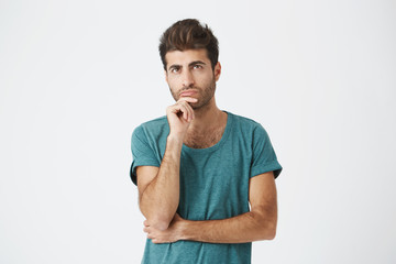 Obraz premium Fashionable, stylish man with dark eyes in casual clothes looking aside with placid and thoughtful look. Pensive guy with puzzled expression thinking about something or building plans.