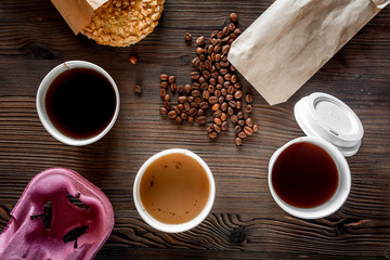 Coffee take out. Coffee cups with covers, coffee beans and cookies on wooden table backound top view