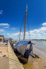 An old ship with a mast. Covered with tarpaulin. Moored at the shore at low tide. Topsham. Devon. England
