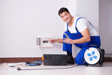 Young electrician working on socket at home