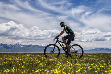 Fototapeta na wymiar A man riding a bike outdoors. Mountain Song Kol lake.