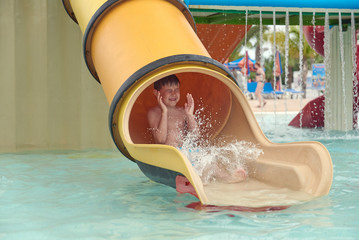 Boy sliding down slide in waterpark.