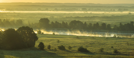 Foggy summer morning over the valley, fog and rising sun