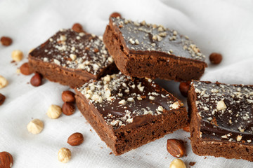 Many pieces of brownie with nuts on white background