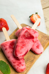 Fresh homemade strawberry ice cream on wooden background. Organic and vegan popsicles