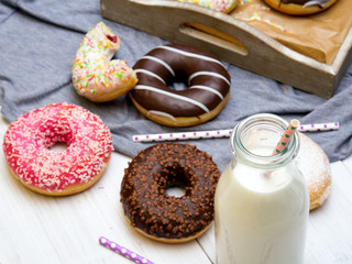 Bottle of milk and colorful donuts with chocolate and icing, selective focus