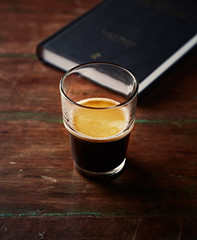 Glass of Espresso and a Book on an old Wooden Table