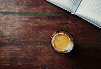 Glass of Espresso and a Book on an old Wooden Table