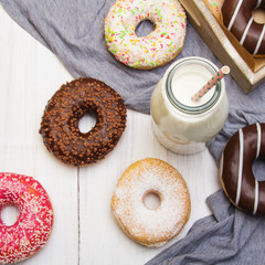 Bottle of milk and colorful donuts with chocolate and icing, selective focus