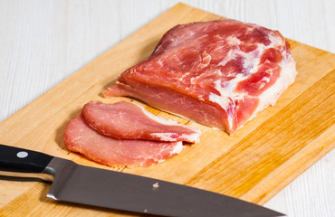 chef knife and raw meat at the wooden board