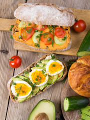 Sandwiches with avocado, eggs and tomato on a wooden background. Fresh organic vegetables, eggs and whole wheat bread. Healthy breakfast. Retro style.