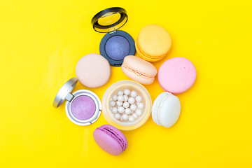 Composition of cosmetics and macaroons on a yellow background