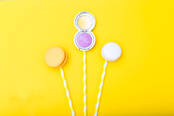 Bouquet of eye shadow and macaroons on a yellow background. flat lay