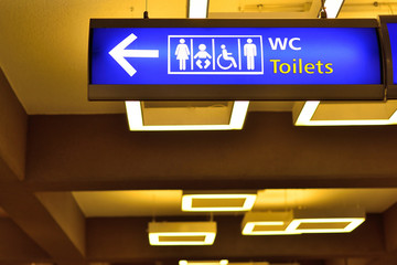 Detailed view of blue airport sign wc directions.