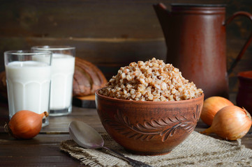 Buckwheat in a bowl with milk on a wooden background