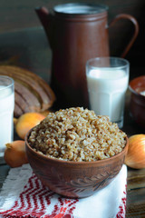Buckwheat  porridge in a bowl with milk on a wooden background